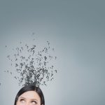 Top of a woman's head with question marks floating above it