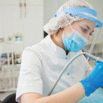 A female dentist performs a surgery dressed in full PPE