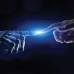 A robot and human hand touch at the index finger.