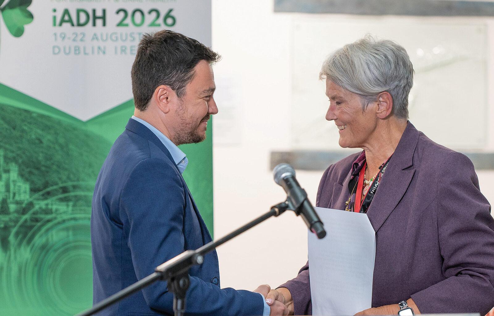 Dr Kamenov and Prof Dougall shake hands on stage.